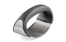 A handheld garlic press with a curved black handle and a stainless steel grating surface. Description generated by AI